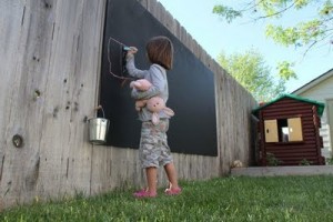 child drawing on an outdoor chalkboard